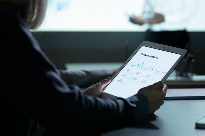 A person reviewing account activity on a tablet in a dim meeting room
